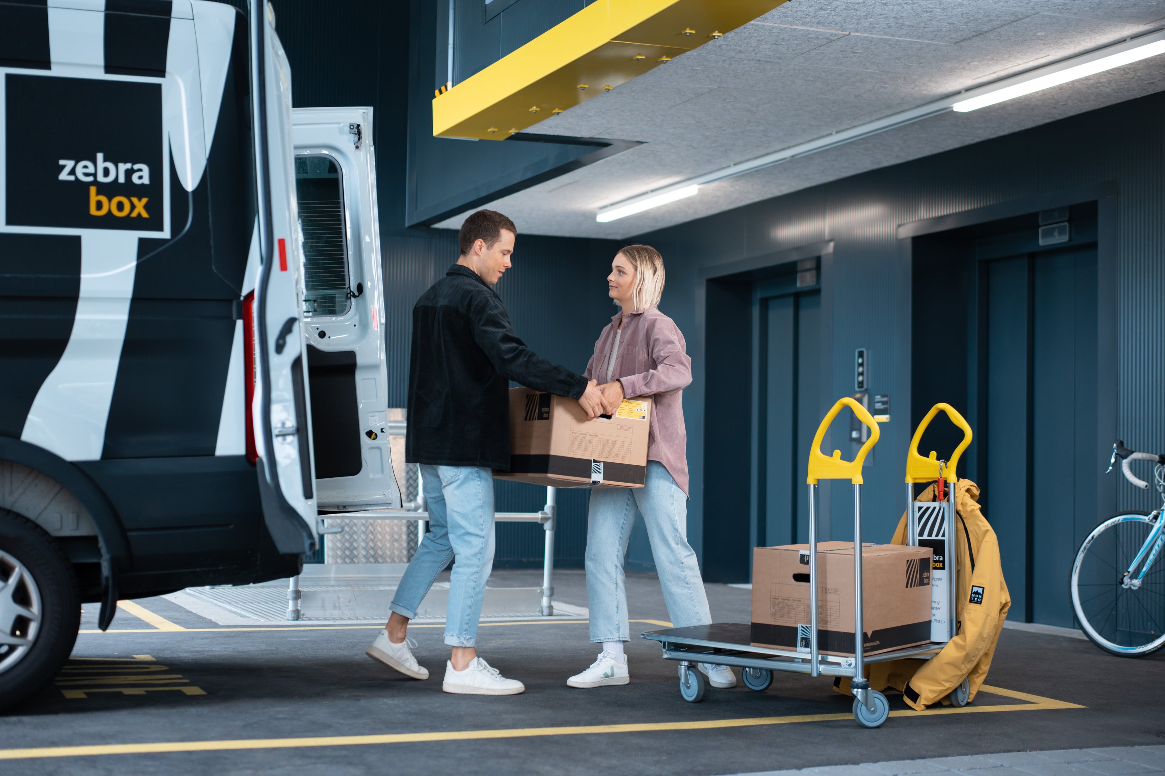 Young couple unloading a sofa from a Zebrabox van.