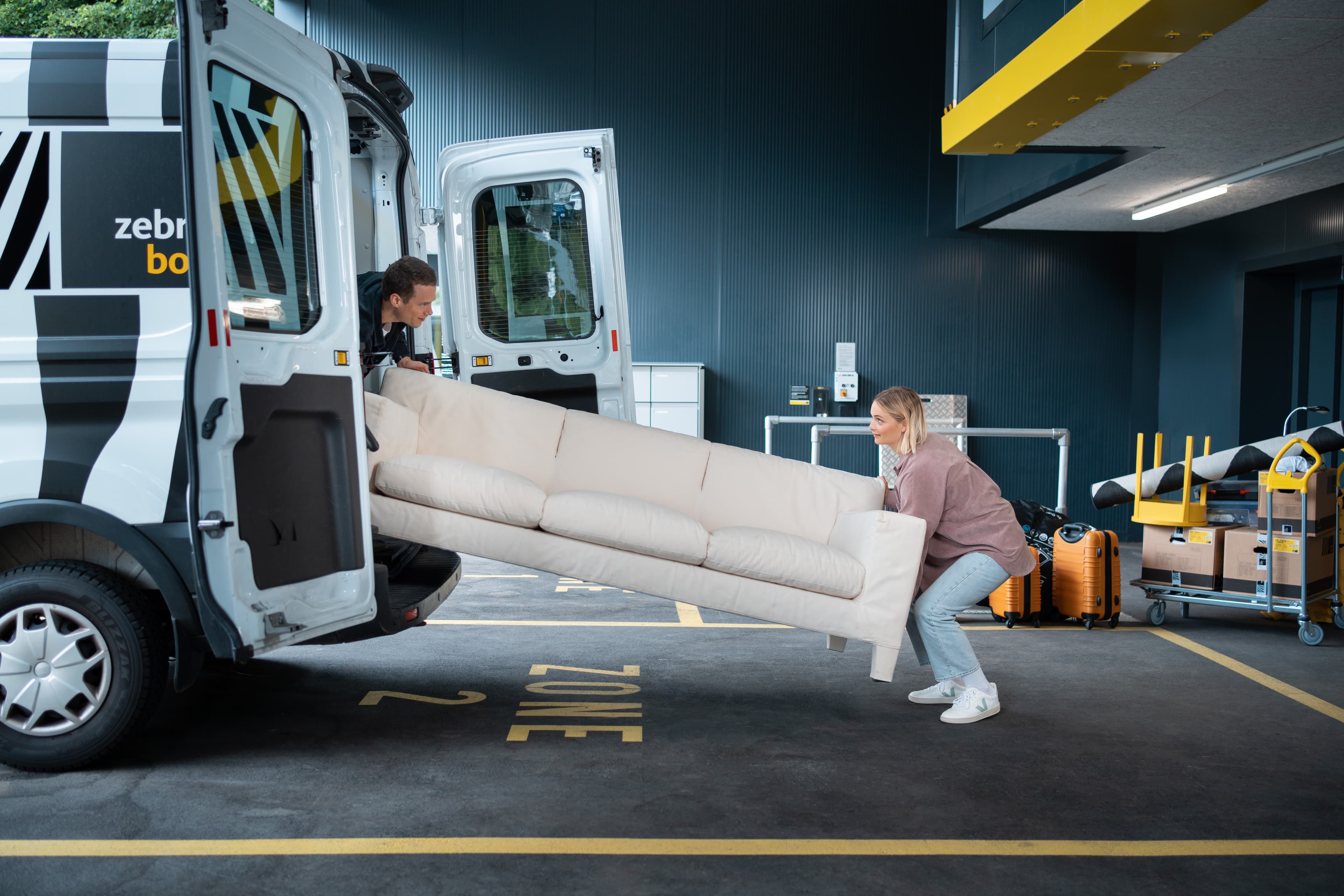 Young couple unloading a sofa from a Zebrabox van.
