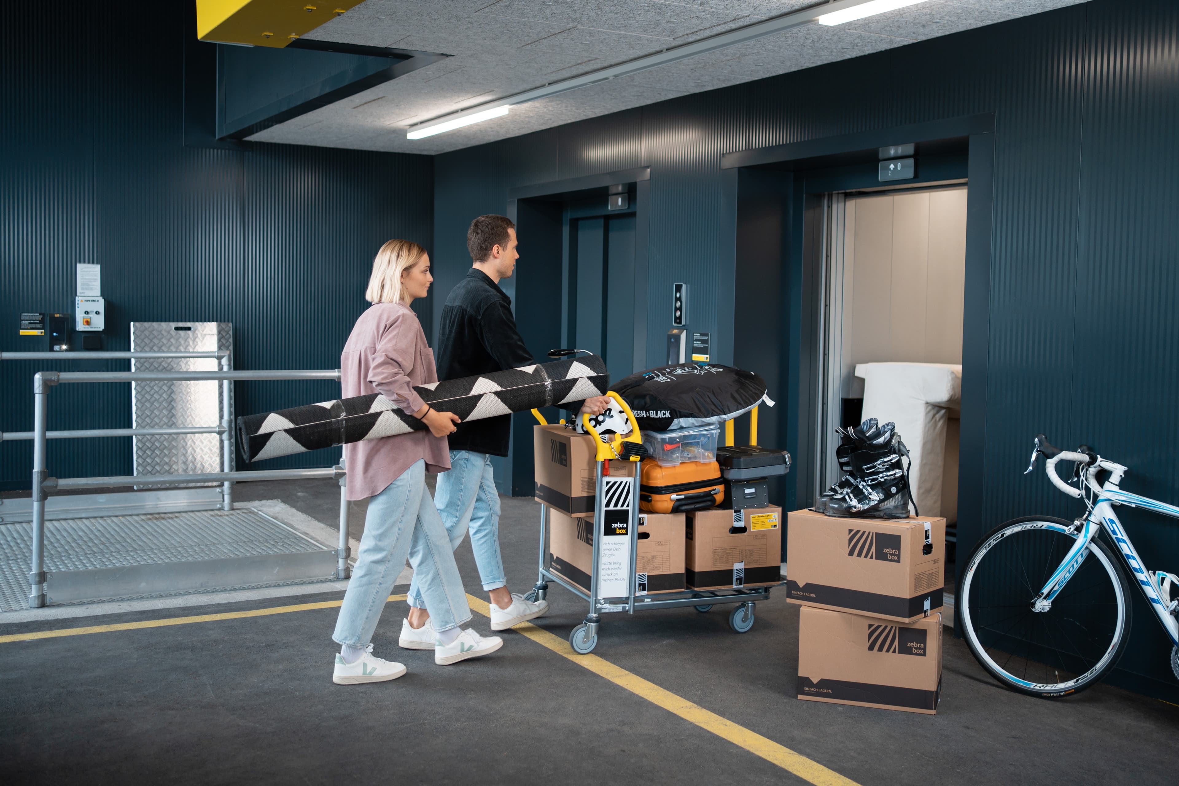 Pareja joven transportando enseres domésticos y cajas de mudanza en el montacargas de Zebrabox.