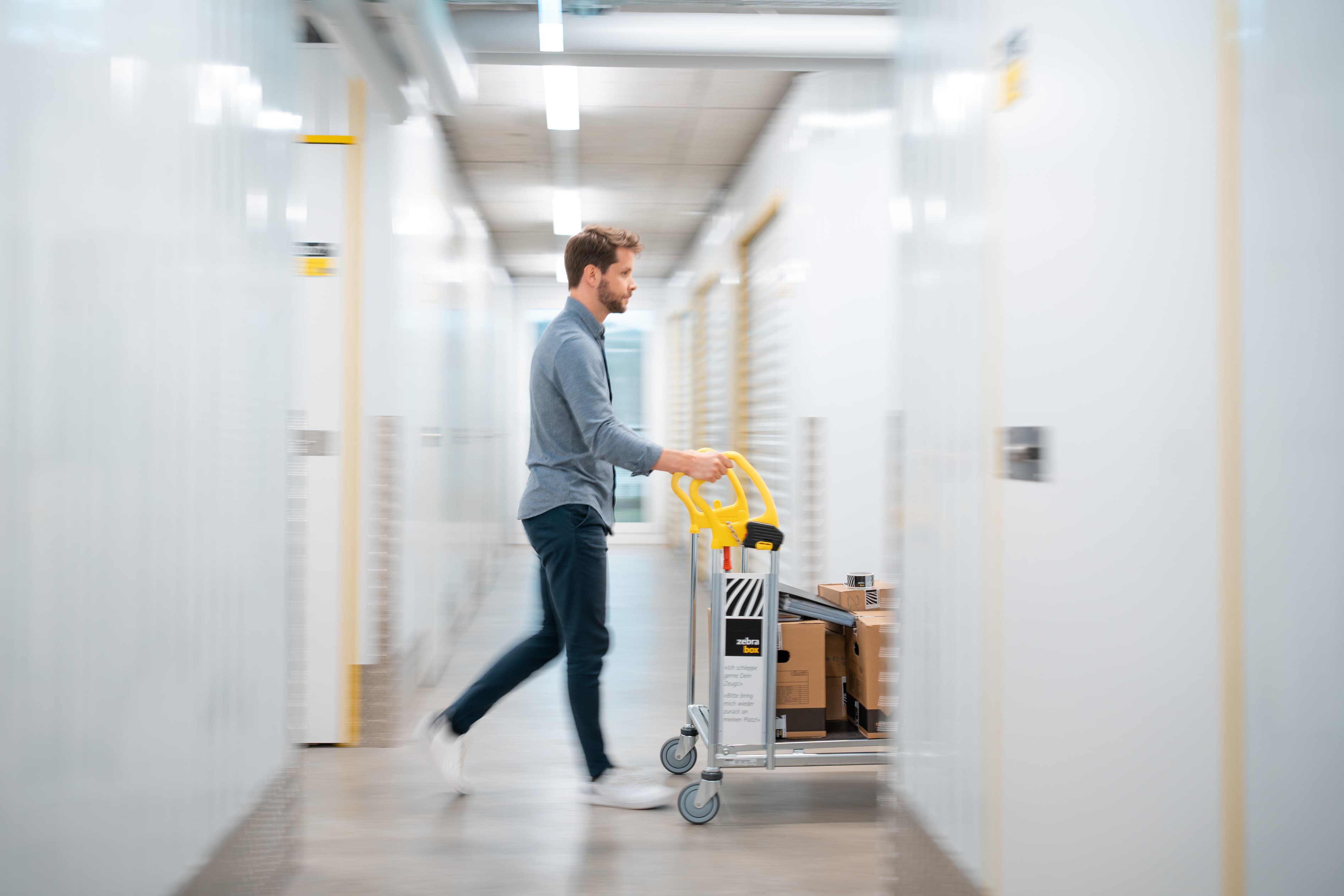 A man is pushing a trolley with moving boxes through the Zebrabox warehouse.
