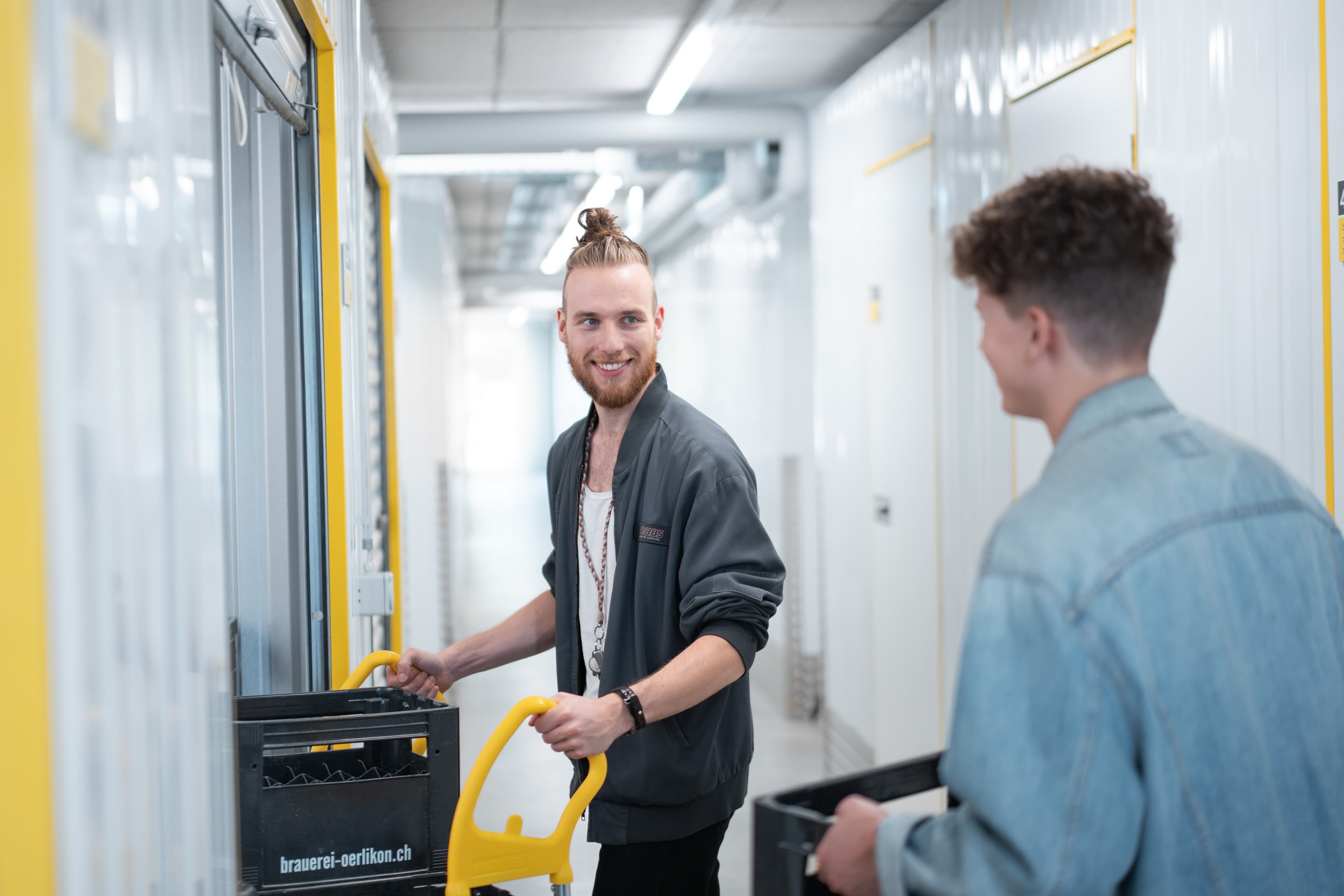 Dos hombres llevan bidones y cajas a su trastero en Zebrabox.