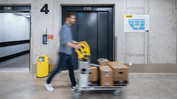 A young man is exiting the lift with a trolley in a Zebrabox location