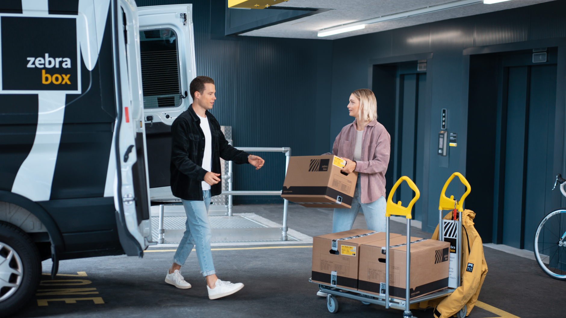 Young couple unloading household and personal effects and moving boxes from a Zebrabox trolley.