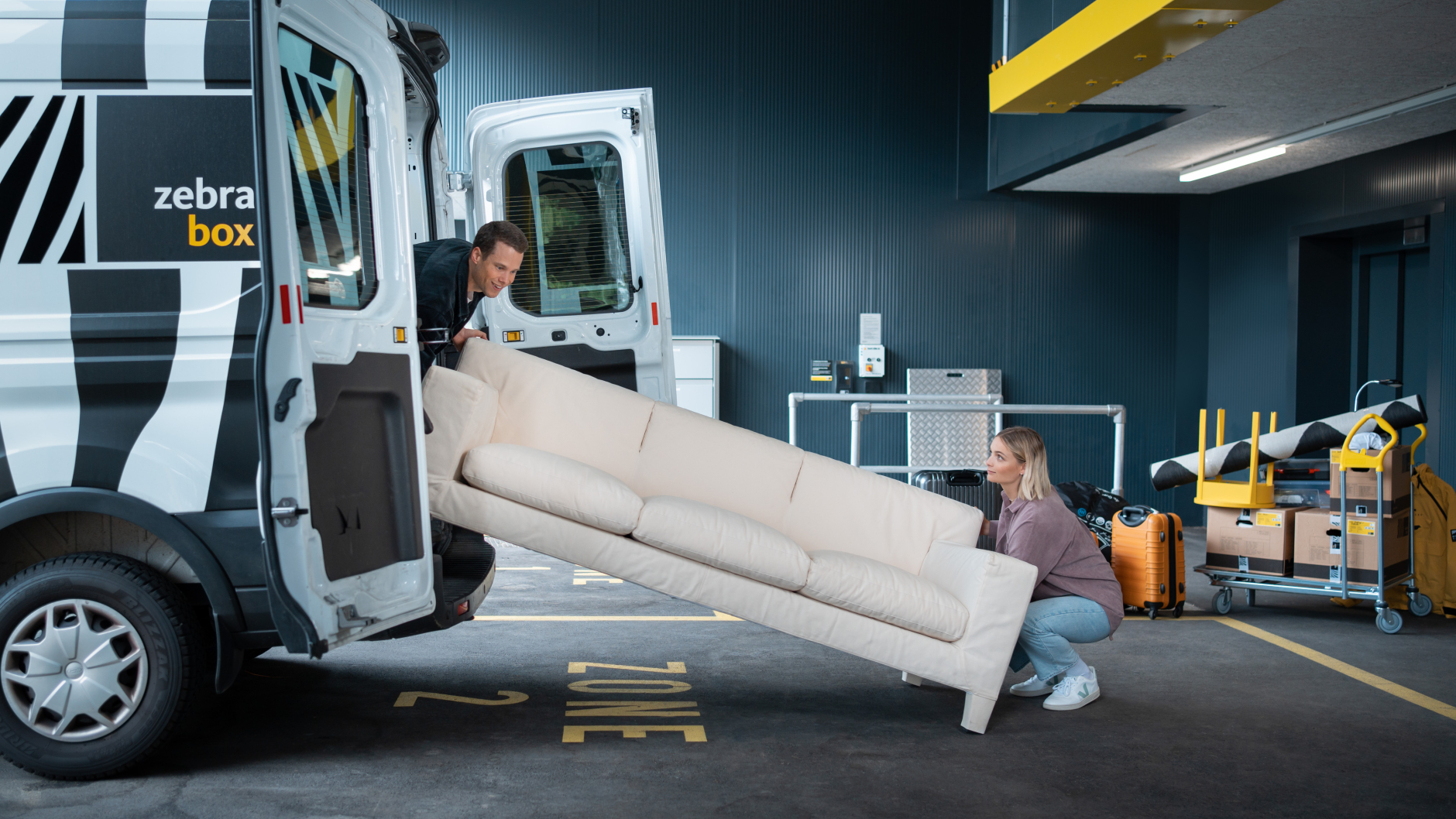 Young couple unloading a sofa from a Zebrabox van.