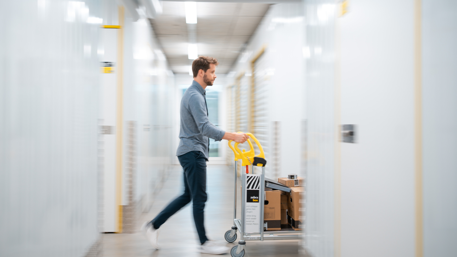 A man is pushing a trolley with moving boxes through the Zebrabox warehouse.