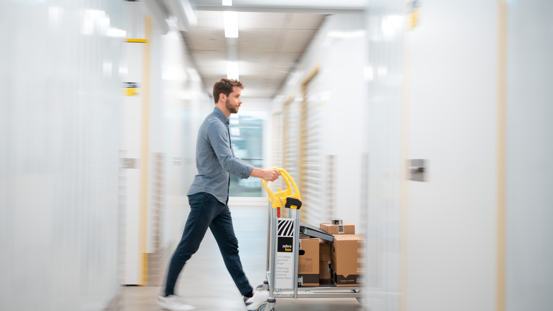 A man is pushing a trolley with moving boxes through the Zebrabox warehouse.